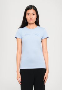 Lichtblauwe aansluitende T-shirt van zacht materiaal, met korte mouwen en een ronde halslijn, waarop "Armani Exchange" in het blauw is geborduurd.