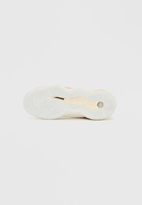 Suola di sneaker bianca con motivo ondulato, colori a contrasto in accenti rossi e crema, con scanalature testurizzate per la trazione.