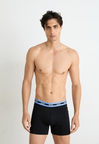 Boxer briefs de algodón negro con una banda elástica azul que presenta la marca "HUGO", diseño ajustado y una textura suave.