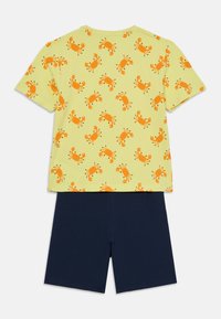 Gelbes Baumwoll-T-Shirt mit orangefarbigem Krabbenprint, kombiniert mit marineblauen Shorts. Kurze Ärmel und lässige Passform, geeignet für warmes Wetter.