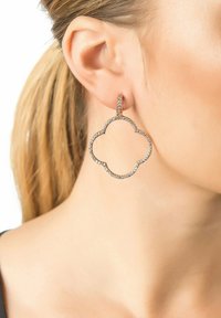 Rose gold hoop earrings feature a cloud shape, adorned with sparkling clear crystals along the edge, hanging from a slender vertical post.