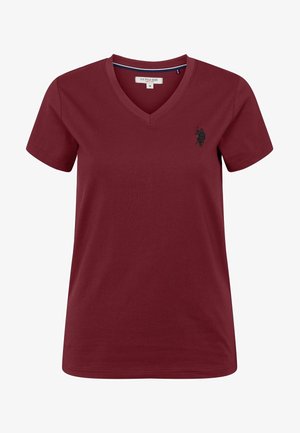 Burgundowa bawełniana koszulka z dekoltem w serek, krótki rękaw i małe czarne haftowane logo po lewej stronie klatki piersiowej. Gładka faktura.