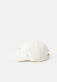 Cappello in corduroy color crema con visiera curvata, logo ricamato sul davanti e cinturino regolabile sul retro. Presenta cuciture a vista.