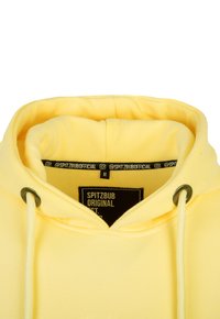 Gelbe Kapuzenjacke mit einer weichen Textur, verstellbaren Kordeln, Metallbeschlägen und einem Markenlabel am inneren Kragen. Größe M.