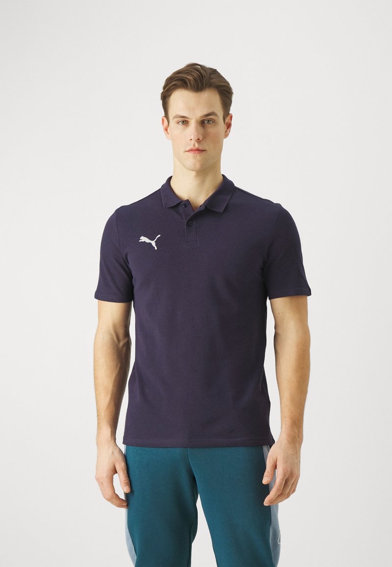 Marineblaues Poloshirt mit kurzen Ärmeln, auf dessen linker Brust sich ein weißes Puma-Logo befindet. Es besteht aus Baumwolle, hat einen klassischen Kragen und eine glatte Textur.