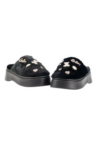 Zapatillas de casa de peluche negro con suela gruesa negra, adornadas con acentos dorados y plateados en forma de oso y corazón.