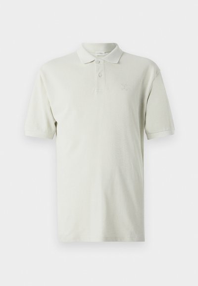 Polo shirt beige clair à manches courtes, col classique et patte de boutonnage à trois boutons. Logo subtil brodé sur la poitrine. Tissu en coton extensible.