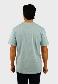 Mintgroene T-shirt met korte mouwen, ronde hals, relaxte pasvorm en gestructureerde stof. Achteraan is een gladde afwerking te zien met een minimaal ontwerp.