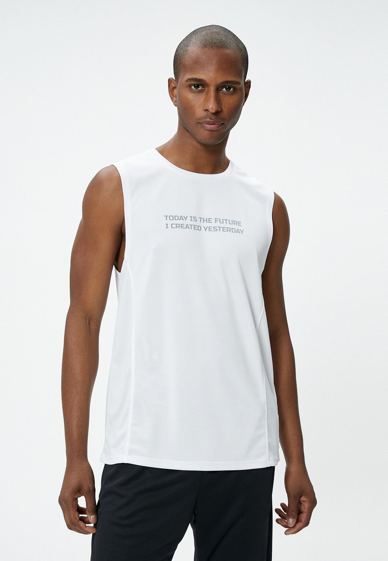 Camisa atlética sin mangas blanca con un escote redondo y un gráfico en la parte frontal que dice "HOY ES EL FUTURO QUE CREÉ AYER". Textura suave.