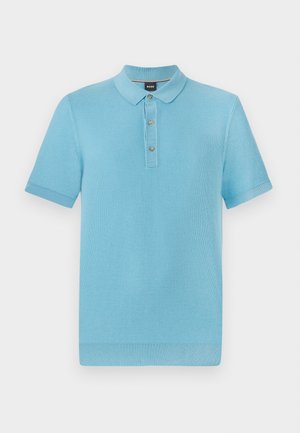 Polo de color azul claro con mangas cortas, tejido texturizado, tapeta de tres botones y cuello y puños de canalé.
