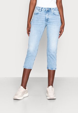 Ljusblå denim capri-jeans med fem fickor, dragkedja och en figurnära design, i kombination med ljusrosa sneakers.