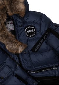 Marinblå puffjacka med konstlädertrim, som har en broderad patch, dragkedjestängning och märkta remmar. Tydlig kviltad textur och fickor.