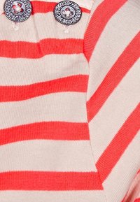 Gestreifter Pullover in Rot und Creme mit zwei runden, silbernen Knöpfen am Ausschnitt und einem weichen, strukturierten Stoff.