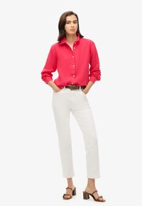 Rode, lange mouwen button-up shirt; gecombineerd met witte, rechte broek; bruine riem; bruine haksandalen; gladde textuur en op maat gemaakte pasvorm.