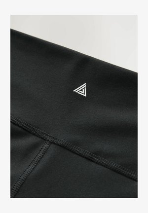 Tissu athlétique noir avec une texture lisse, arborant un petit logo triangulaire blanc et une couture contrastante au niveau de la taille.