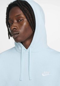 Felpa leggera azzurra con lacci, con un piccolo logo Nike bianco sul petto. Realizzata in un tessuto morbido con una vestibilità comoda.