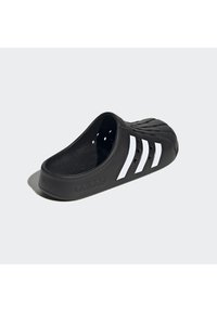 Sandalin neri senza chiusura realizzati in materiale sintetico, con design a tre strisce bianche, fori di ventilazione e logo del marchio stampato sul lato.