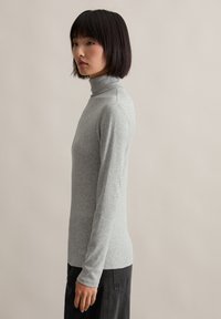 Grijze lange mouwen turtleneck shirt van een zachte, elastische stof. Aansluitend ontwerp met geribbelde manchetten en een naadloze neklijn.
