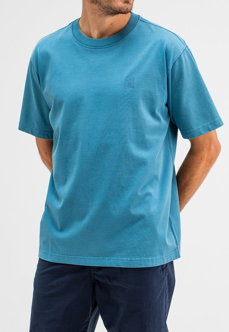 Kurze Ärmel, türkisfarbenes Baumwoll-T-Shirt mit rundem Halsausschnitt und einem kleinen Logodetail auf der Brust. Schlichte und legere Passform.