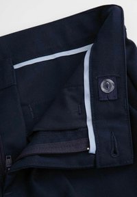 Granatowa tkanina z zapięciem na guziki i suwakiem. Jasnoniebieski akcent na pasie, z widocznym przeszyciem i teksturowanym wnętrzem.