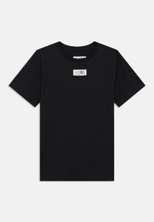 T-shirt de algodão preta com gola redonda e mangas curtas. Apresenta uma pequena etiqueta impressa no peito. Textura suave, ajuste casual.