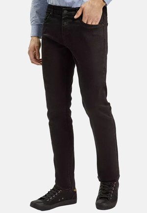 Czarne dżinsy o slim fit, z pięcioma kieszeniami i delikatną teksturą. W połączeniu z czarnymi trampekami.