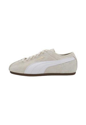 Zapatilla Puma de ante beige con raya blanca, cierre de cordones y suela marrón, vista desde el lateral exterior.