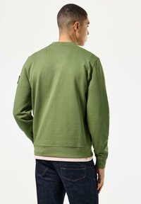 Grüner Baumwoll-Sweatshirt mit langen Ärmeln, Rundhalsausschnitt und geripptem Saum. Verfügt über ein schwarzes Etikett am linken Ärmel und eine strukturierte Oberfläche.