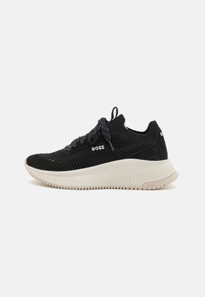 Czarny, dziany niskoprofilowy sneaker z grubą białą podeszwą, czarnymi sznurowadłami, pętelką na pięcie i logo "BOSS" z boku oraz z tyłu.