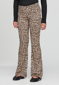 Pantaloni a zampa di elefante in stampa leopardata beige con dettagli neri, dotati di una cintura ampia e di una texture morbida. Abbinati a scarpe basse nere.