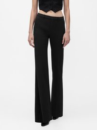 Pantalon noir évasé avec une coupe ajust ée, présentant une texture lisse, des passants pour ceinture et des poches avant. Stylisé avec un haut court.