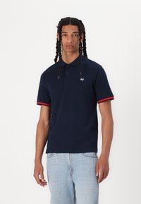 Navy polo shirt with a collared design, featuring red accents on the sleeve cuffs and a small logo on the chest. Made of cotton.
