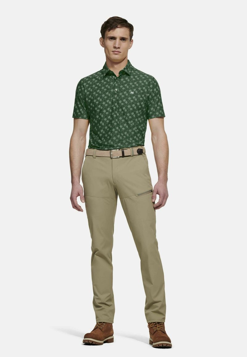Grünes, gemustertes Poloshirt mit kurzen Ärmeln, beigem Hosen und braunen Stiefeln. Das Shirt hat ein geometrisches Muster und einen Kragen.