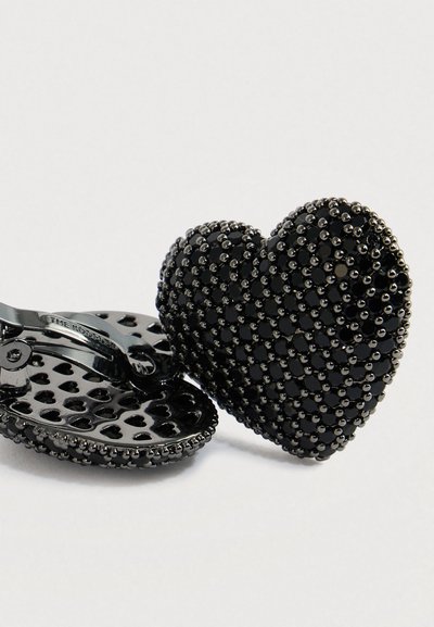 Čierne klipové náušnice v tvare srdca s textúrovanými korálikovými detailmi a hladkým kovovým zapínaním na svetlom pozadí.