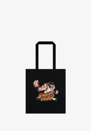 Czarna torba typu tote z muskularnym, animowanym wojownikiem w białym gi, rzucającym cios nad logo „Street Fighter” napisanym pogrubioną czcionką.