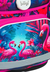 Růžový a modrý batoh s tropickým vzorem zobrazujícím plameňáky, listoví a květiny; zahrnuje světle šedý pásek s logem značky.