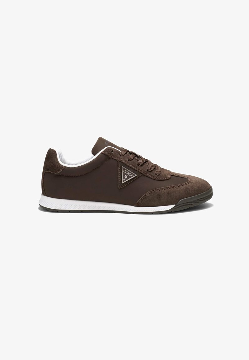 Baskets basses marron avec semelle blanche, fermeture à lacets devant, bout et talon en daim, et un logo Guess triangulaire sur le côté.