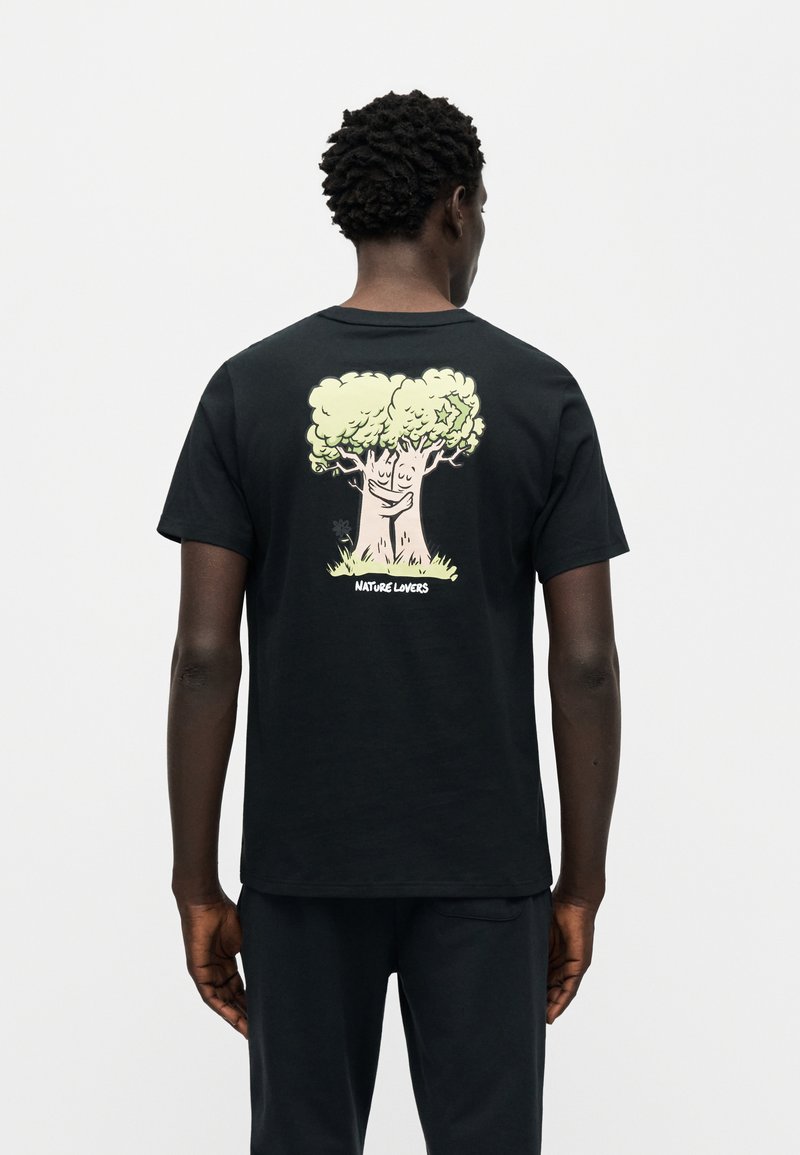 Maglietta nera in cotone con una grafica colorata di un albero sorridente con fogliame verde e la scritta "AMANTI DELLA NATURA" sulla schiena.