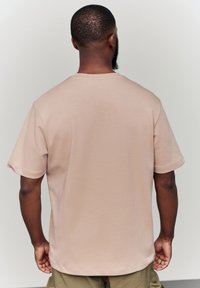 Short-sleeve t-shirt in beige fabric, featuring a crew neckline and relaxed fit, with a smooth texture and minimal detailing.