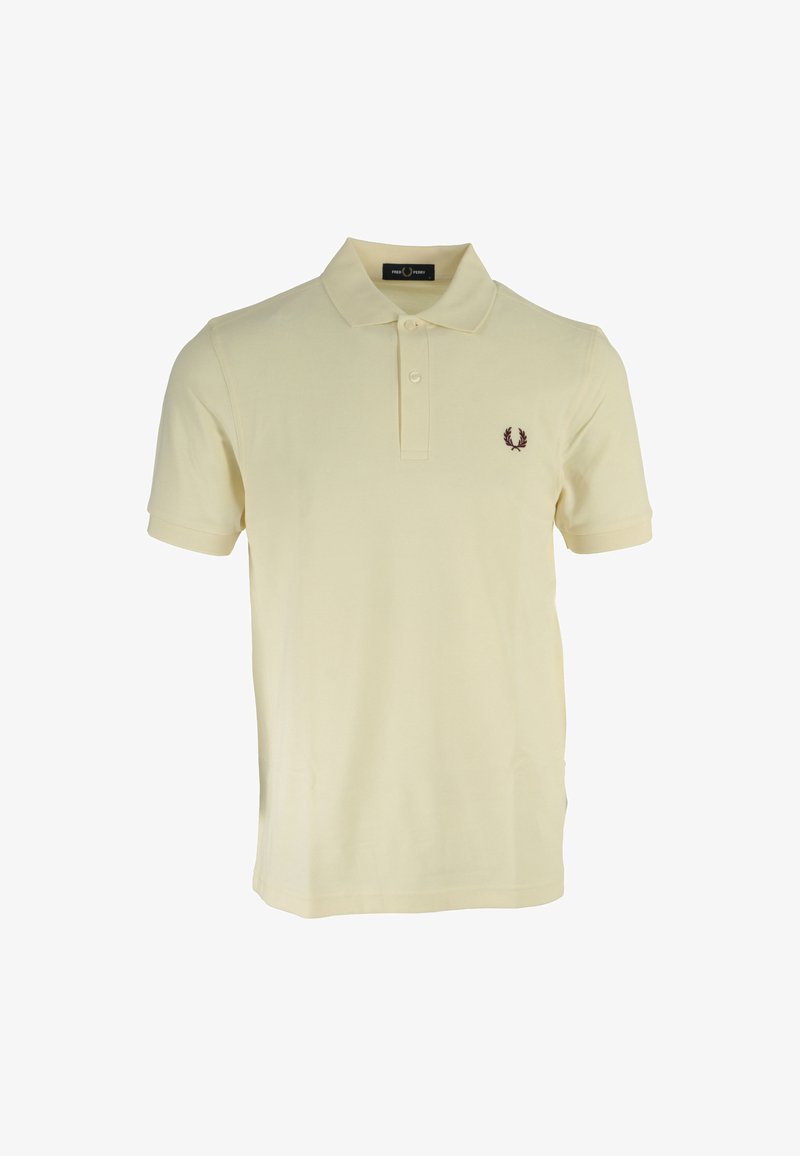 Polo shirt jaune pâle en coton ; il comporte une patte de boutonnage à trois boutons et un petit logo brodé en rouge foncé sur la poitrine gauche.