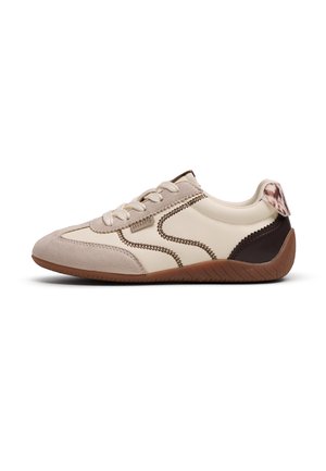 Sneaker beige e marrone con profilo basso, cuciture laterali a zigzag, punta in camoscio, chiusura frontale con lacci e dettaglio decorato sul tallone su sfondo bianco.