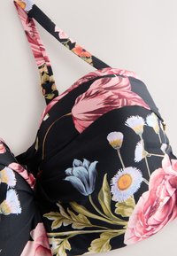 Mustast kangast lillemustriga rinnahoidja, millel on roosad, sinised ja valged lilled. Reguleeritavad rihmad ja kogutud disain tekstuurse detailiga.