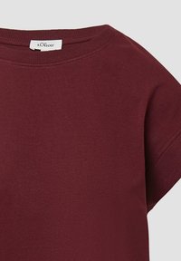 Bordeaux roter Kurzarm-Sweatshirt mit rundem Ausschnitt und gerippten Abschlüssen. Weiche Stoffoberfläche, mit einem Etikett am Kragen.