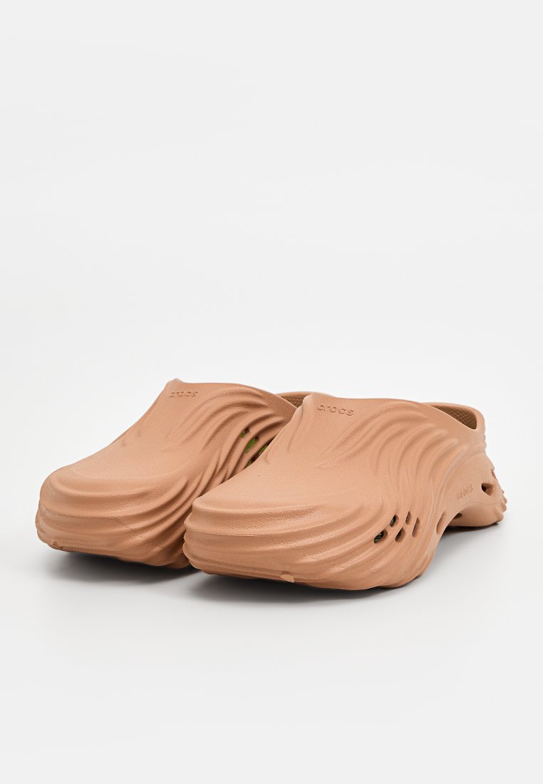 Zoccoli in gomma marroni con texture ondulata, apertura sul retro e perforazioni laterali per la ventilazione, caratterizzati da un design a profilo basso.