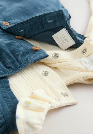 Baby-Outfit aus blauem Cord und cremefarbenem strukturiertem Stoff mit Holzknöpfen und Druckknopfverschluss, mit floralen Mustern auf dem Innenfutter.