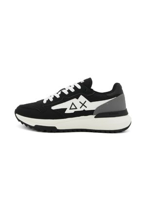 Baskets noires avec accents blancs, présentant une tige texturée, un col rembourré et une épaisse semelle intermédiaire blanche. Le logo sur le côté est visible.