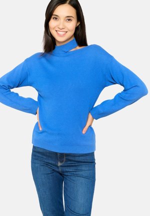 Pull en tricot bleu avec un col montant, des manches longues et une coupe décontractée, associé à un jean en denim. Texture douce et couleur vive.