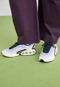 Sport sneakers with a textured fabric upper in light blue, pink gradients, black laces, and a white cushioned sole featuring six air pockets.