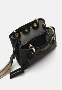 Czarna skórzana torebka z złotymi akcentami, z podwójnymi uchwytami, paskiem w paski oraz otwartym wnętrzem, które odsłania szare wykończenie i kieszeń wewnętrzną.