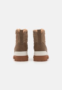 Botas de tobillo marrones con acolchado en el collar, cuero texturizado y una suela intermedia blanca. Presenta una suela de goma con estrías para mayor tracción.